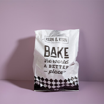 Brottüte im Corporate Design von Kern & Korn mit der Aufschrift Bake the world a better place