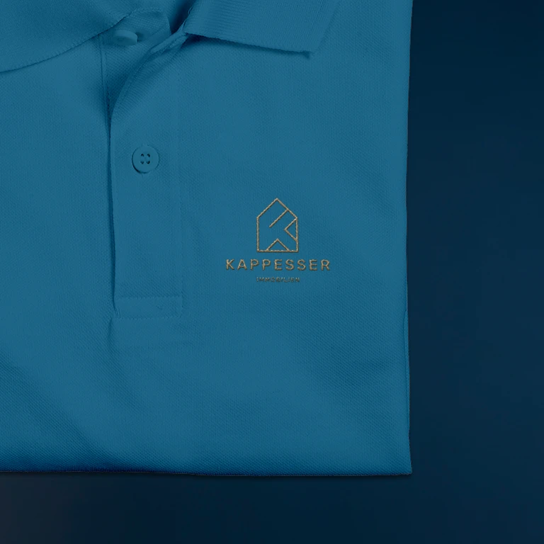 Nahaufnahme des mit dem Logo bestickten Poloshirts von Kappesser Immobilien