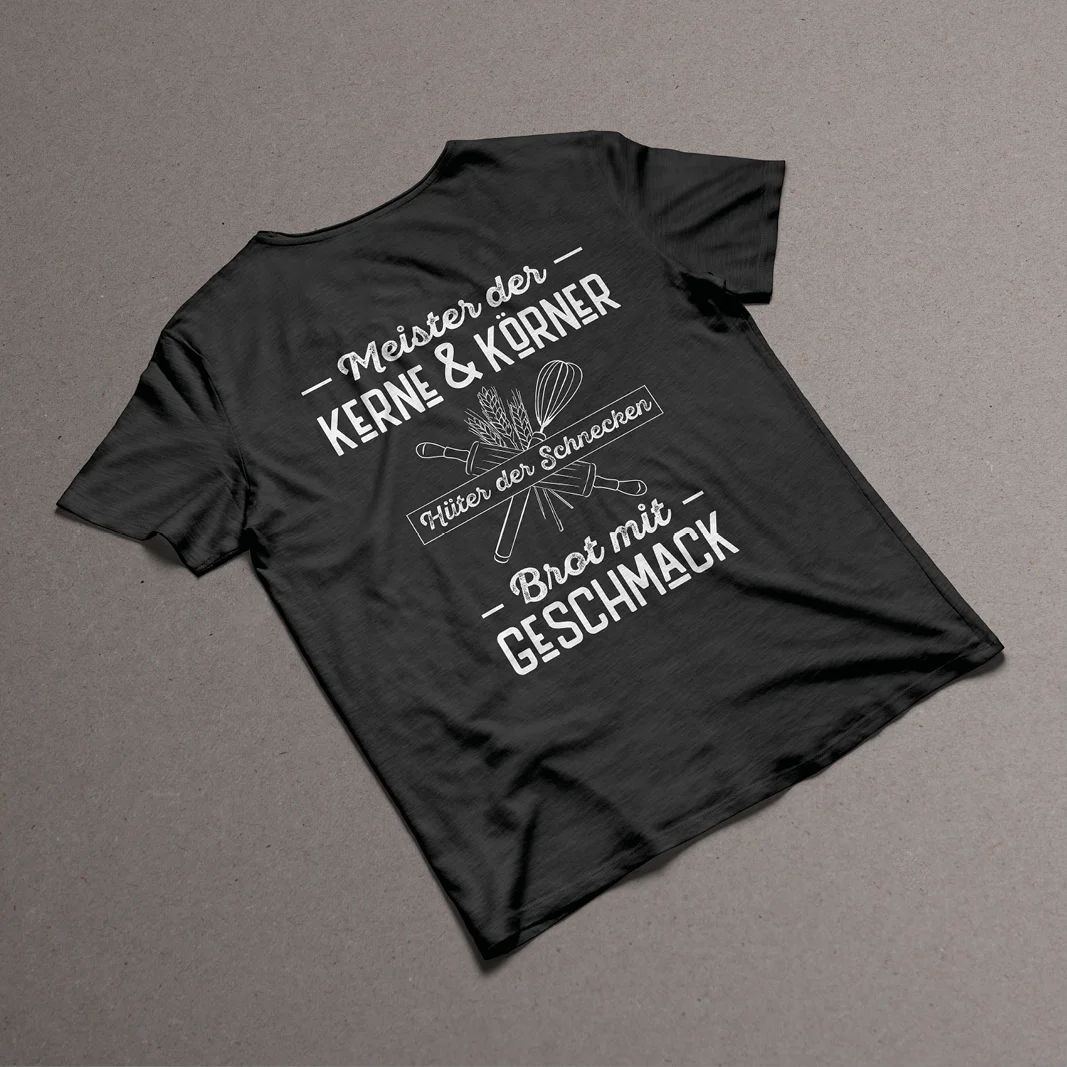 schwarzes T-Shirt von Kern & Korn mit der Aufschrift "Meister der Kerne & Körner - Hüter der Schnecken - Brot mit Geschmack"